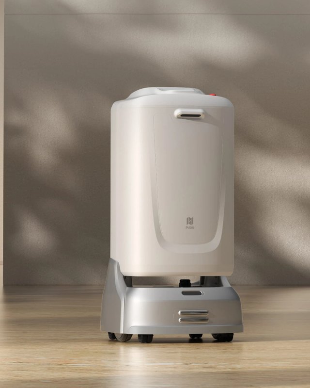 Official Pudu product render of the FlashBot Max in a hotel lobby — a cream-white cabinet-shaped delivery robot with a large front compartment door carrying the PUDU logo, a recessed handle, a red status light on the roof, and a silver four-wheel base